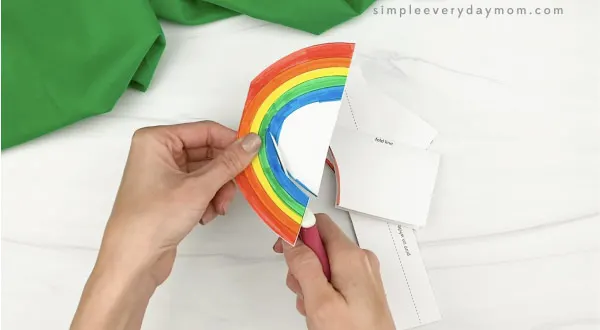hands cutting out rainbow card craft