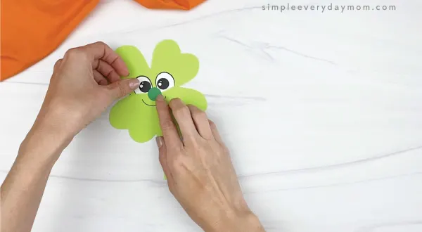 hand gluing nose onto leprechaun shamrock