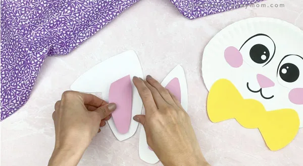 hand gluing inner ears to paper plate Easter bunny craft