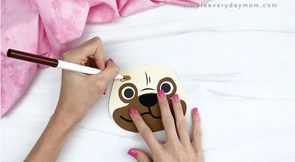 hands drawing eyebrows onto puppy valentine craft