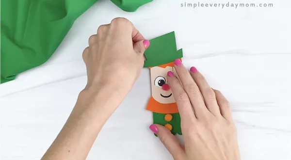 hand gluing hat on hand gluing hair to popsicle stick leprechaun craft