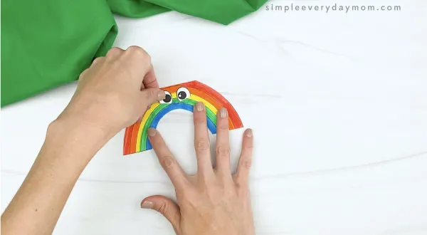 hand gluing eyes to rainbow card craft