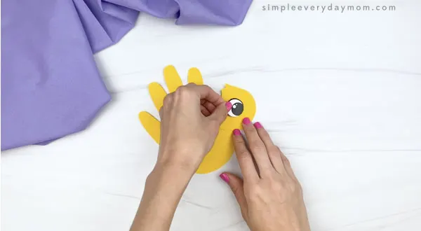 hand gluing eye to handprint chick