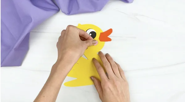 hands gluing cheek to handprint duck craft