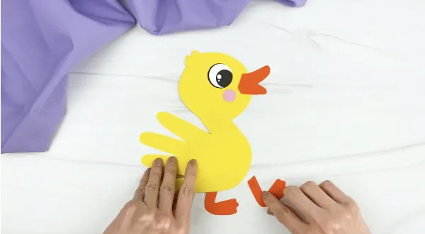 hands gluing feet to handprint duck craft