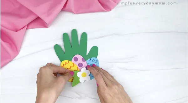 hand gluing flower to handprint Easter card craft