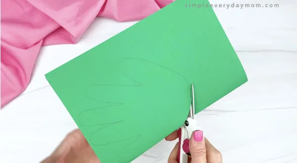 hand cutting out handprint from green paper