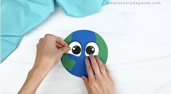 hand gluing eyes to paper Earth craft