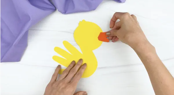 hands gluing bill to handprint duck craft
