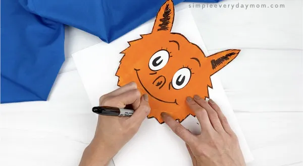 hand outlining fox in socks craft with black marker