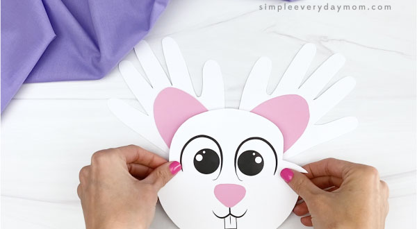 hand gluing bunny head to handprint ears