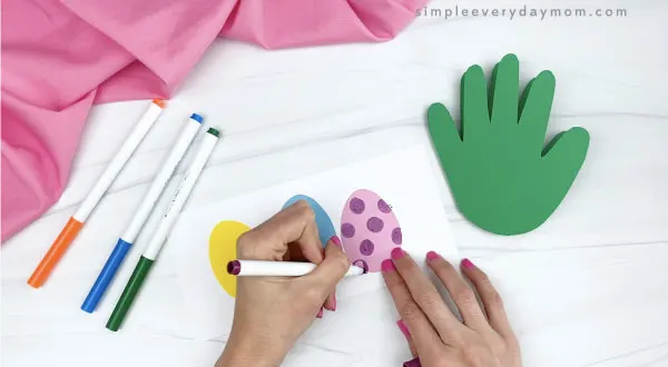 hand decorating paper easter eggs with markers