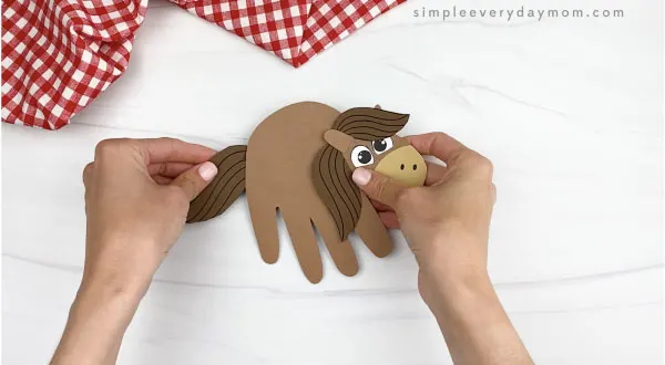 hand gluing tail to handprint horse craft