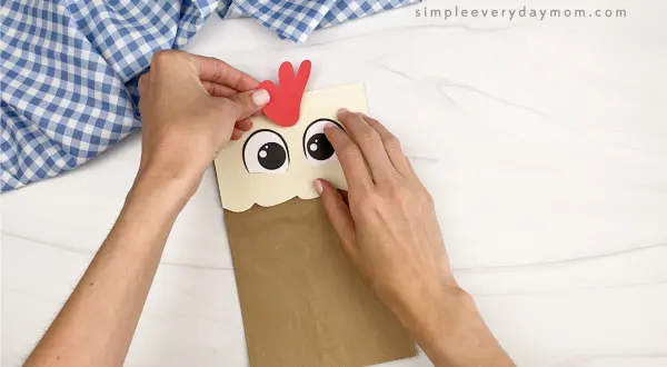 hand gluing comb to paper bag chicken craft