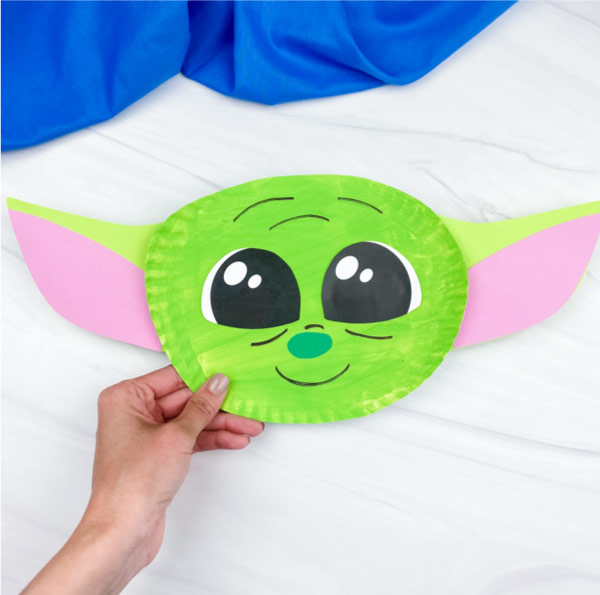hand holding paper plate baby yoda craft
