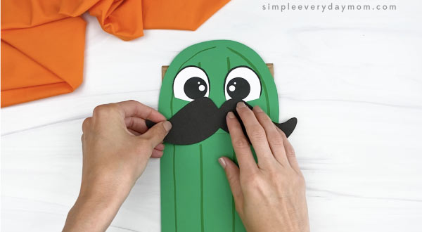 hand gluing mustache to paper bag cactus craft