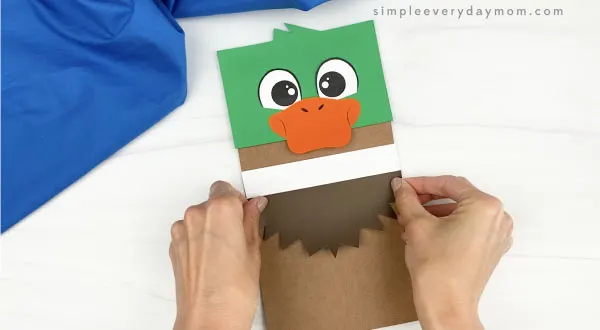 hand gluing feathers to duck paper bag craft