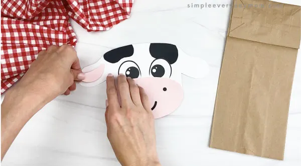 hand gluing inner ears to paper bag cow craft