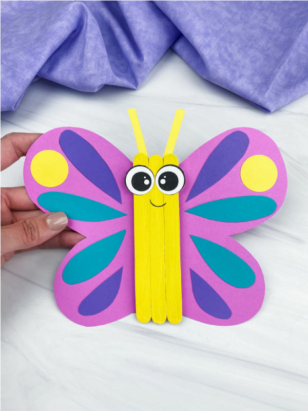 hand holding popsicle stick butterfly craft