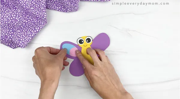 hand gluing wing decorations to butterfly stick puppet