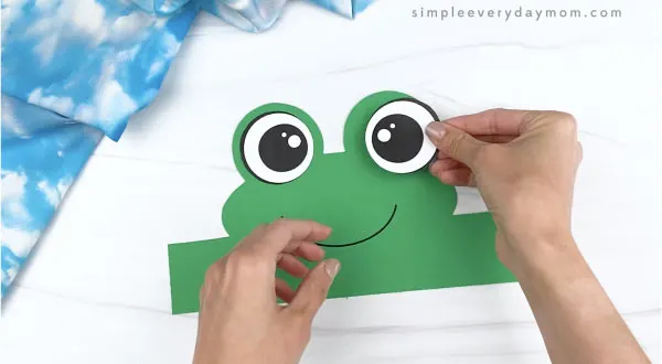 hand gluing eye to frog headband craft