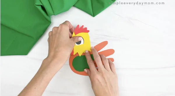 hands gluing head to handprint rooster craft