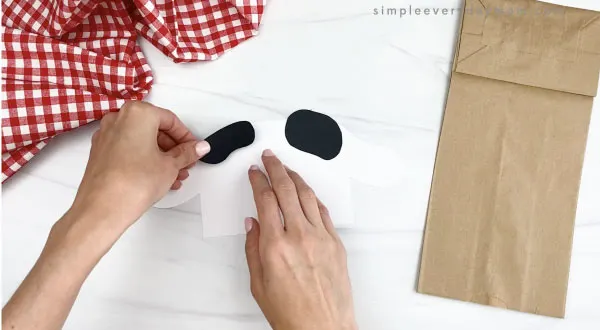 hand gluing spots to paper bag cow head craft