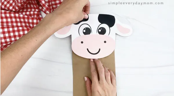 hand gluing head to paper bag cow craft