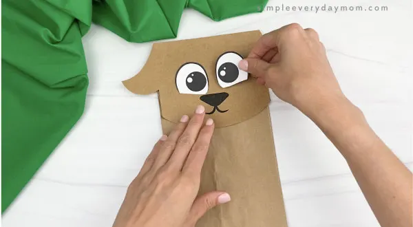 hand gluing eye to paper bag goat craft