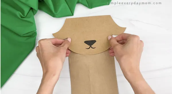 hand gluing head to paper bag goat craft