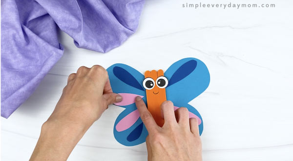 hand gluing wing decorations to popsicle stick butterfly craft