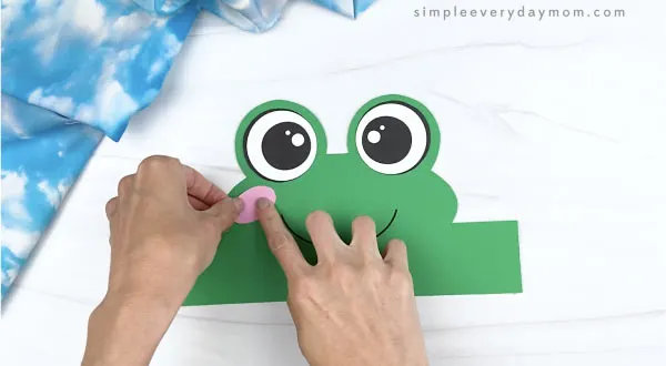 hand gluing cheek to frog headband craft
