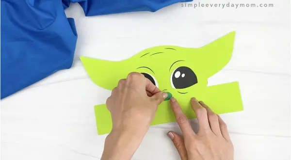 hands gluing nose to Baby Yoda headband craft
