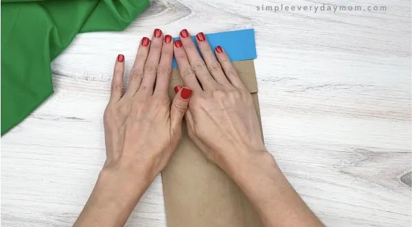 hand gluing blue rectangle to paper bag beluga craft