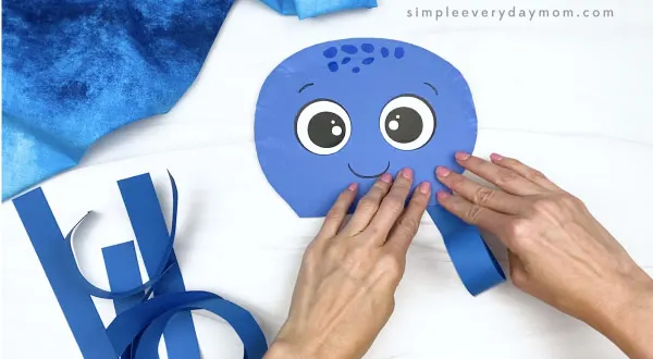 hand gluing tentacles onto paper plate octopus craft