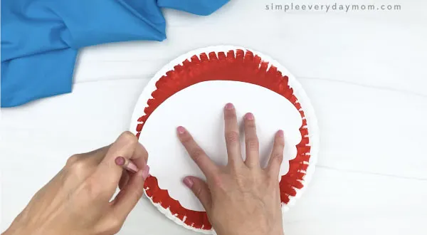 hand tracing crab body template on red paper plate