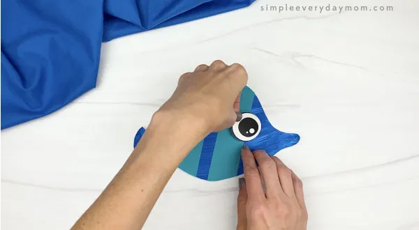 hand gluing eye to paper plate fish
