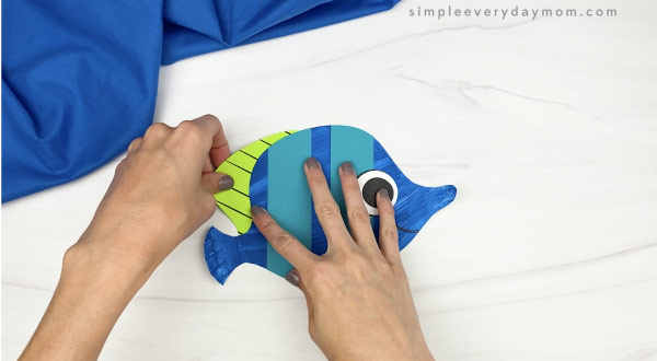 hand gluing top fin to paper plate fish