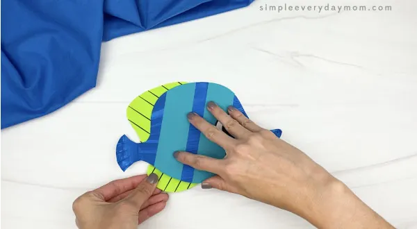 hand gluing bottom fin to paper plate fish
