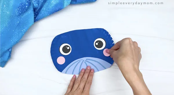 hand gluing cheek onto paper plate whale craft