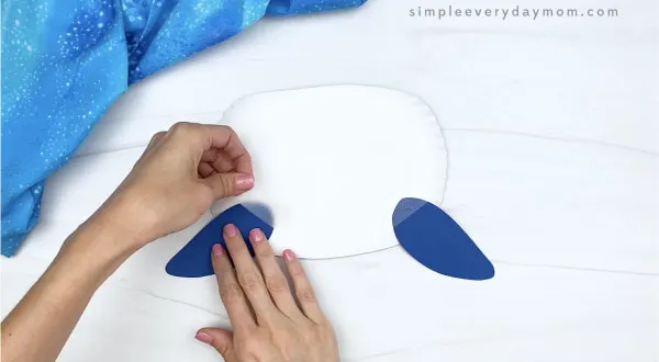 hand taping fins to paper plate whale craft