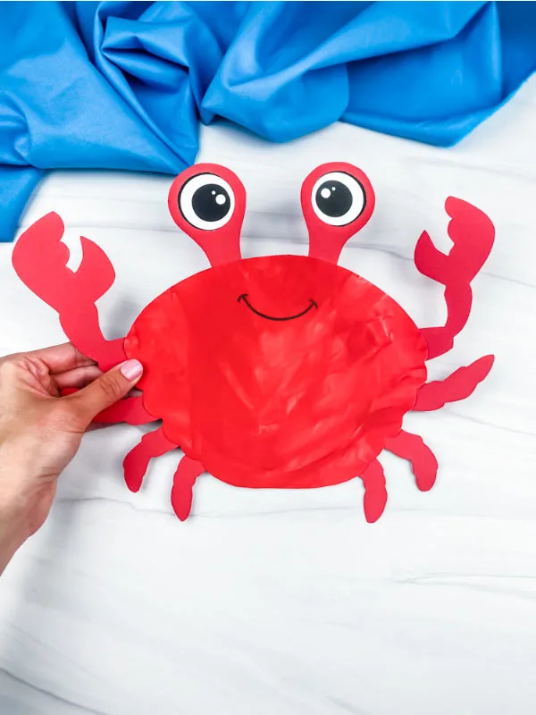 hand holding paper plate crab craft