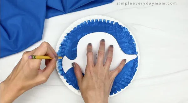hand tracing fish template on paper plate fish craft