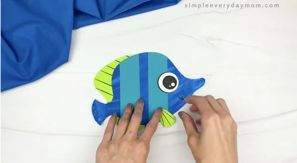 hand gluing side fin to paper plate fish