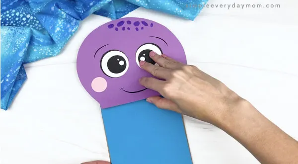 hand gluing blue paper to paper bag octopus