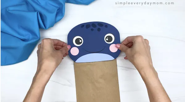 hands gluing head to paper bag whale craft