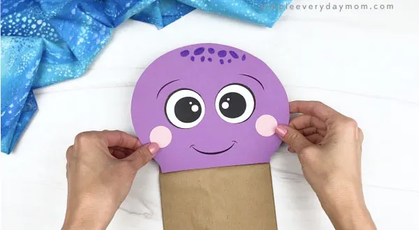 hand gluing head to paper bag octopus