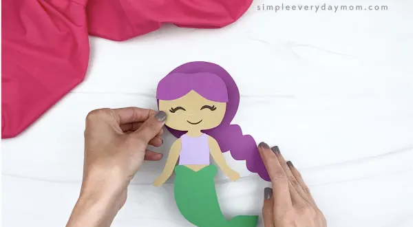 hand gluing mermaid body to mermaid hair