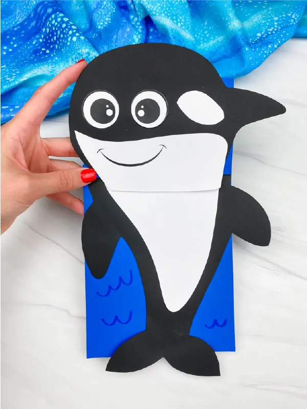 hand holding orca paper bag puppet craft