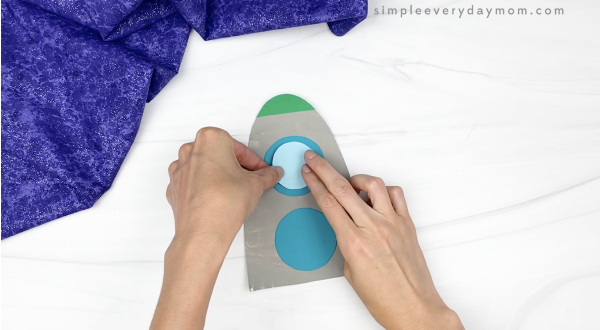 hand gluing window to paper plate rocket craft
